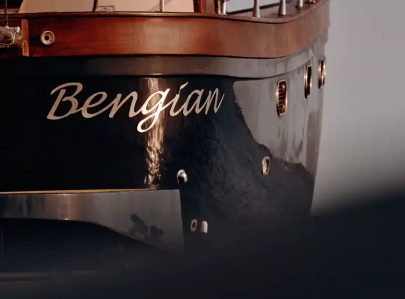 Detalle del nombre "Bengian" sobre el casco de madera lacada en azul