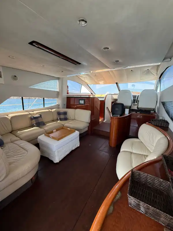 Salón interior del Fairline Phantom 50 con sofás de piel y madera de caoba