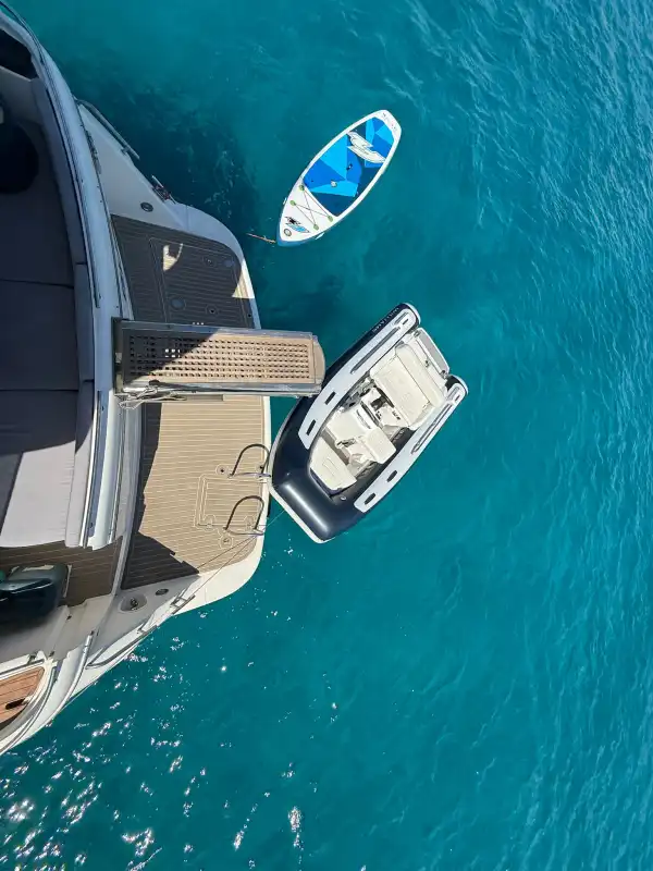 Vista aérea del Fairline Phantom 50 con tender y paddle surf sobre agua cristalina
